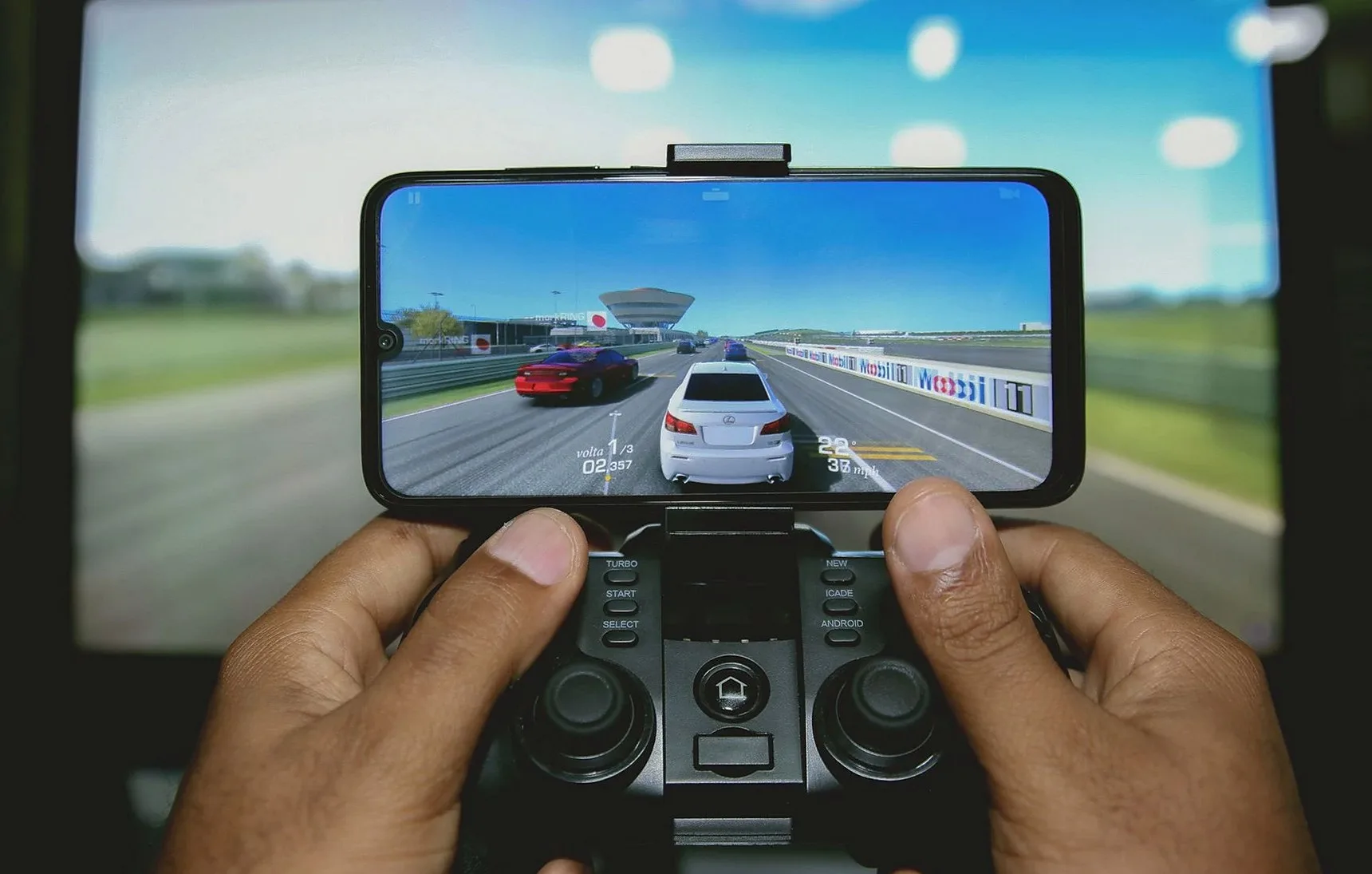 コントローラーを使ってモバイルデバイスでレーシングゲームをプレイする手のクローズアップ
