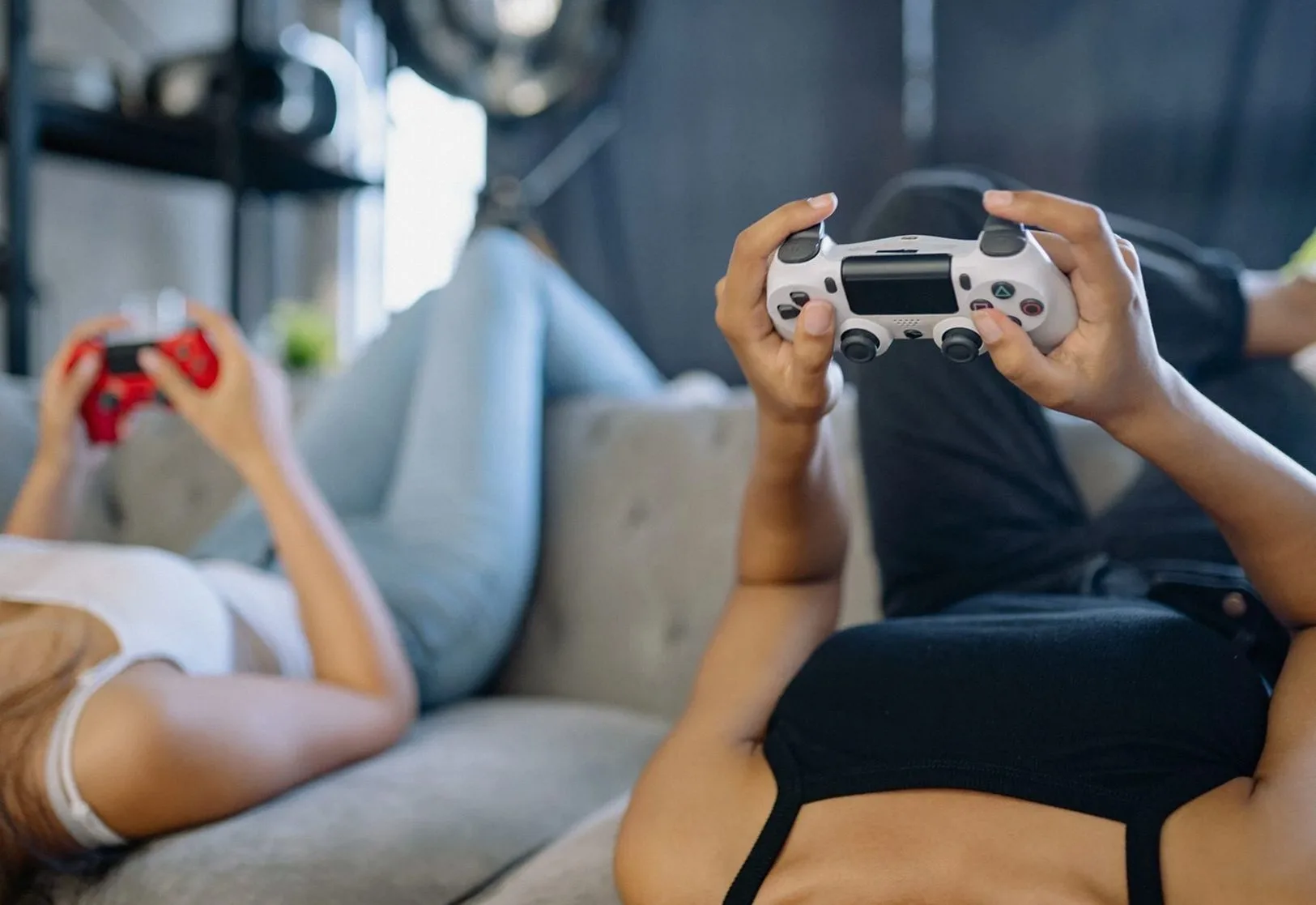 ソファに寝転んでゲームのコントローラーを持つ二人